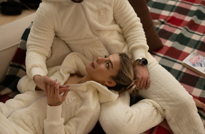 couple laying down on couch wearing fuzzy onesies